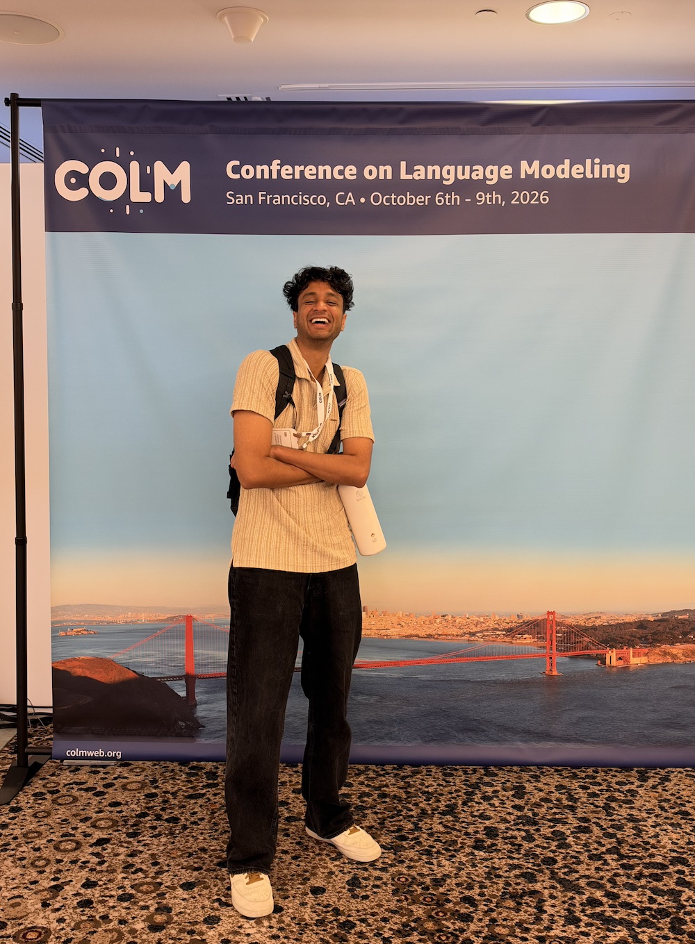 Shubham Kumar in front of the COLM 2026 conference banner
